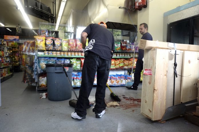 h_51384629-696×464 A store employee cleans up the mess from a broken planter that fell off the counter.